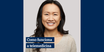 mulher usando camiseta cinza sorrindo e ao seu lado a escrita "como funciona a telemedicina" em uma caixa azul
