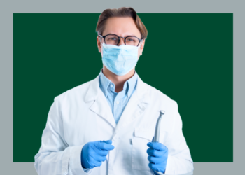 homem de máscara e jaleco branco segurando um aparelho de dentista