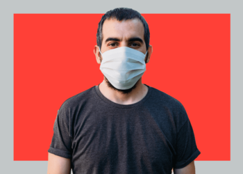 homem com máscara em frente a fundo vermelho e cinza