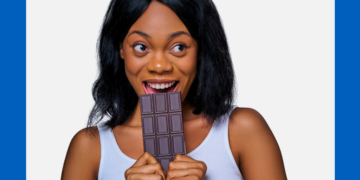 Mulher negra ameaça morder uma barra de chocolates sobre um fundo branco e azul.