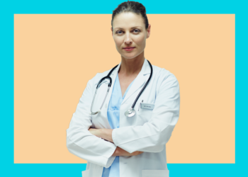 Médica de jaleco e braços cruzados olha pra câmera sobre um fundo bege e azul