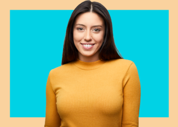 Mulher olha para a câmera sorrindo sobre fundo azul e bege