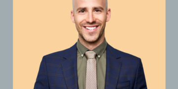 Homem olha para a câmera sobre um fundo cinza e bege