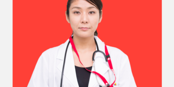 Médica de jaleco olha para a câmera sobre um fundo coral e branco