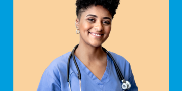 Médica com roupa azul e estetoscópio no pescoço olha para a câmera sorrindo sobre um fundo bege e azul.