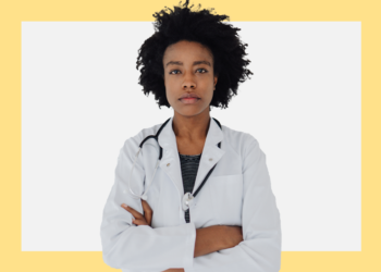 Mulher de jaleco, estetoscópio e de braços cruzados olha para a câmera sobre um fundo branco e amarelo.