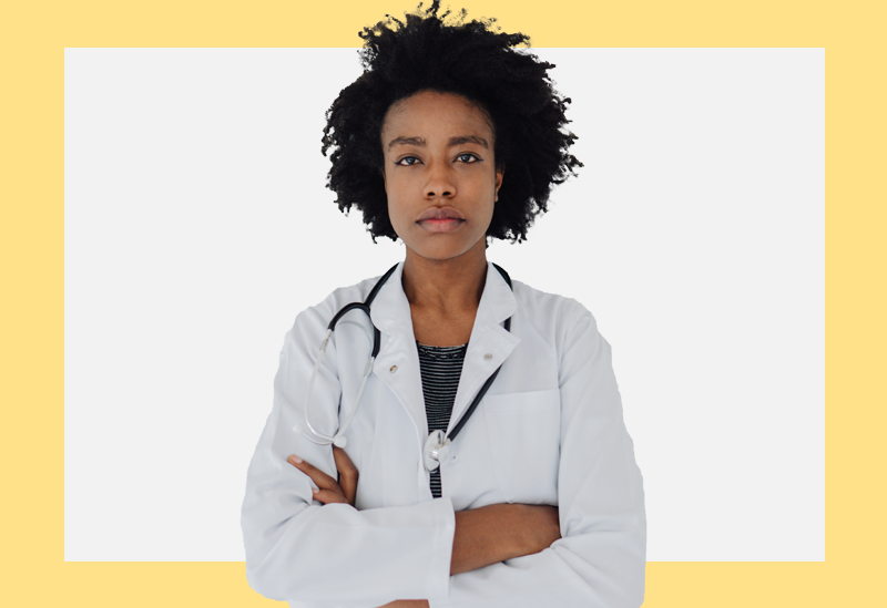 Mulher de jaleco, estetoscópio e de braços cruzados olha para a câmera sobre um fundo branco e amarelo.