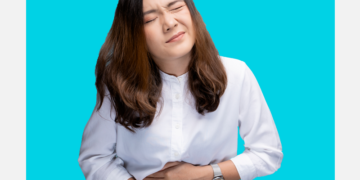 Mulher com dores abdominais sob um fundo azul e branco